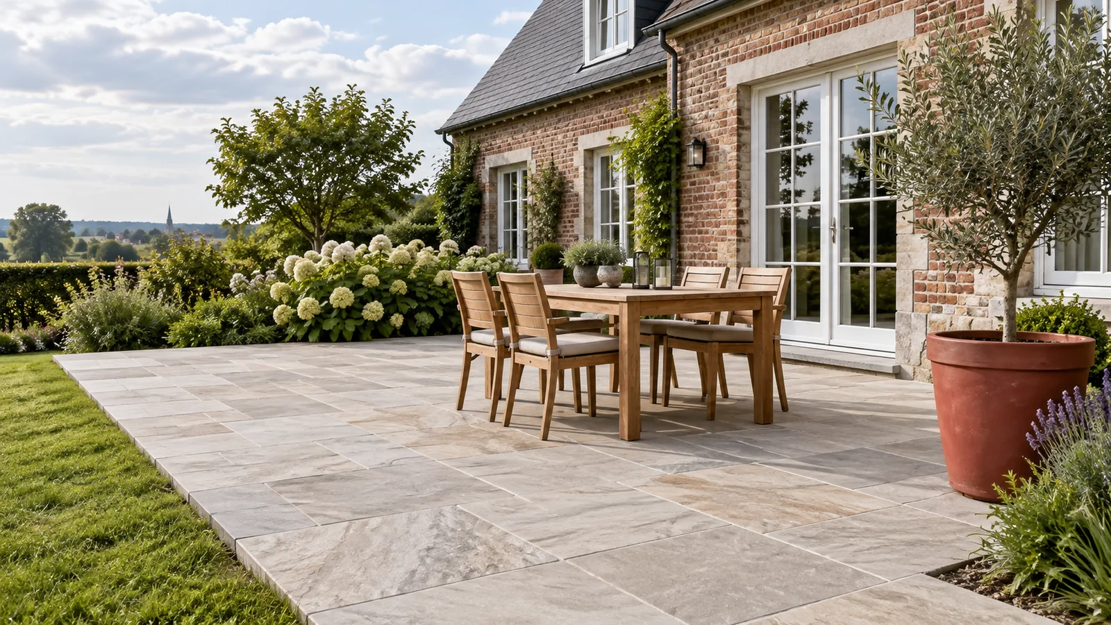 Terrasse en dalles de grès naturel devant une maison en briques